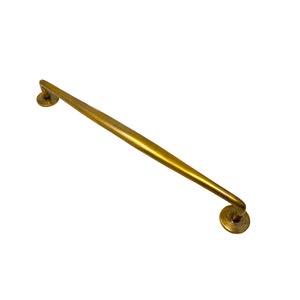 May include: A gold-toned metal door handle with a curved design and rounded ends.