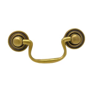 May include: A gold-toned cabinet pull with a rounded, decorative knob on each end. The pull has a simple, curved shape.