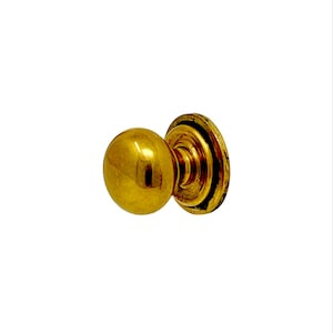 May include: A gold-toned door knob with a round, spherical handle and a flat, circular base.