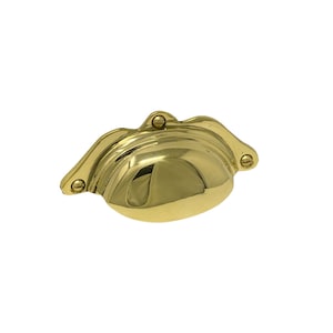 May include: A shiny, gold-colored cabinet pull with a shell-like design. The pull has a curved shape with three small screws for mounting. This hardware is suitable for drawers and cabinets.