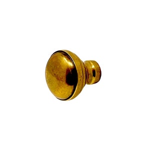 May include: A gold-toned metal knob with a round, slightly domed top and a cylindrical base.