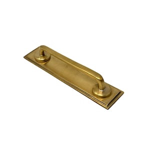 May include: A gold-toned door handle with a rectangular base and a curved handle.