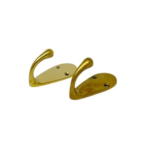 May include: Two gold-toned metal hooks with a rounded base and a single hook on each. The hooks are mounted on a white background.