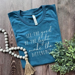 May include: Teal blue t-shirt with white text that reads "See the good, be the light, make the difference."