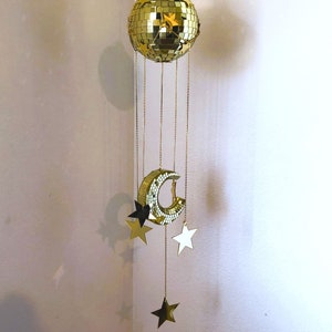 May include: A gold mirrored disco ball mobile with a crescent moon and stars hanging from it.