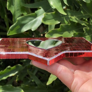 May include: A red mosaic mirror shaped like a heart with a silver glitter border.