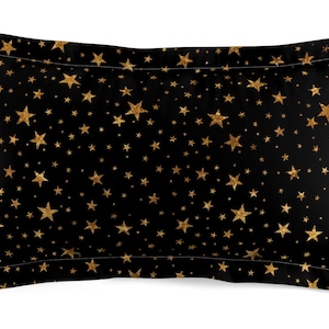 May include: A black pillowcase with a gold star pattern. The stars are of varying sizes and are scattered randomly across the pillowcase.