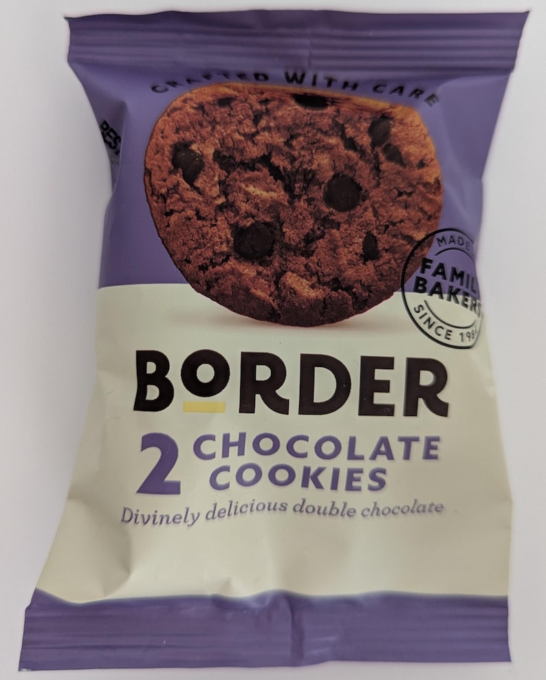 May include: A purple and cream snack package featuring a chocolate chip cookie graphic. The text reads BORDER, 2 CHOCOLATE COOKIES, Divinely delicious double chocolate, CRAFTED WITH CARE, and MADE BY FAMILY BAKERS SINCE 1984 in a circular stamp.