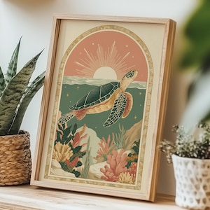 Può includere: Una stampa artistica incorniciata con una tartaruga marina che nuota nell'oceano. L'opera d'arte ha uno stile vintage con una barriera corallina e un sole al tramonto. La cornice è in legno chiaro.