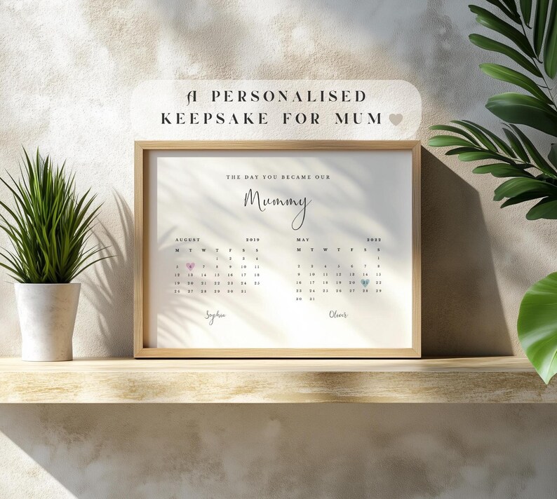 Pu&ograve; includere: Una stampa incorniciata con il testo "A Personalised Keepsake For Mum". La stampa presenta un layout di calendario con la parola "Mummy" in corsivo. Le date di agosto 2019 e maggio 2022 sono evidenziate con cuori.