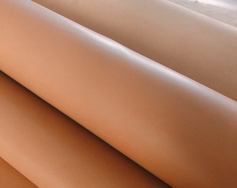 May include: Close-up of a rolled up piece of light brown leather. The leather has a smooth, polished surface.