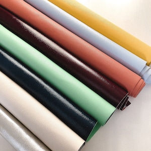 May include: A collection of eight different colored leather strips, including silver, white, beige, green, navy blue, burgundy, red, and yellow.