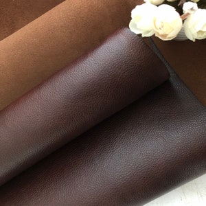 May include: Two pieces of leather fabric, one brown and one dark brown, are folded on top of each other. The dark brown leather has a textured surface.