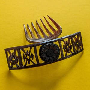 May include: A brown hair comb with a decorative floral design. The comb has a decorative floral design with a black centre.