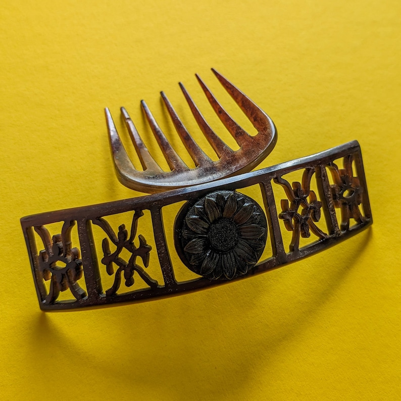May include: A brown hair comb with a decorative floral design. The comb has a decorative floral design with a black centre.