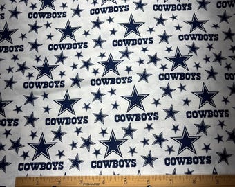 May include: White fabric with a repeating pattern of blue stars and the word "COWBOYS".