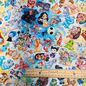 May include: Fabric featuring a colorful pattern of cartoon characters, including Mickey Mouse, Stitch, and others. The design includes a variety of characters on a white and blue background. A ruler is placed on the fabric, showing measurements in inches.