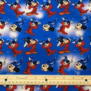 May include: A blue fabric with a repeating pattern of Mickey Mouse dressed as a wizard. He is wearing a red robe, a blue hat with a crescent moon, and is holding a wand. The background is a light blue with white stars.