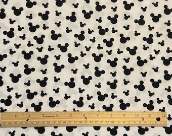 May include: White fabric with a black Mickey Mouse head pattern. The fabric is measured with a ruler that shows 12 inches.