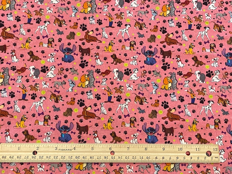 May include: Pink fabric with a repeating pattern of cartoon dogs, paw prints, and bones. Stitch from Lilo & Stitch is also featured in the pattern.