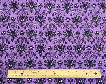 May include: Purple fabric with a repeating pattern of black haunted mansion silhouettes. A ruler is placed at the bottom of the image.