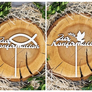 Può includere: Due topper per torta in legno bianco per una festa di conferma. Un topper presenta un simbolo di pesce con il testo "Zur Konfirmation". L'altro topper presenta una colomba con un ramo di ulivo e il testo "Zur Konfirmation".