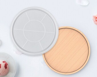 Può includere: Due vassoi rotondi, uno in silicone bianco con sei sezioni e uno in legno naturale.