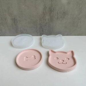 May include: Three silicone molds for making resin crafts. Two molds are pink and feature a dog face and a bone. The third mold is white and features a dog face.