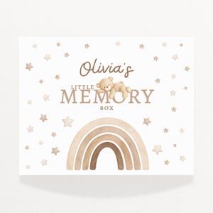 May include: A rectangular box featuring the text "Olivia's Little Memory Box" in brown script and block letters. A watercolor rainbow and a teddy bear are featured. The background is white with scattered star shapes.