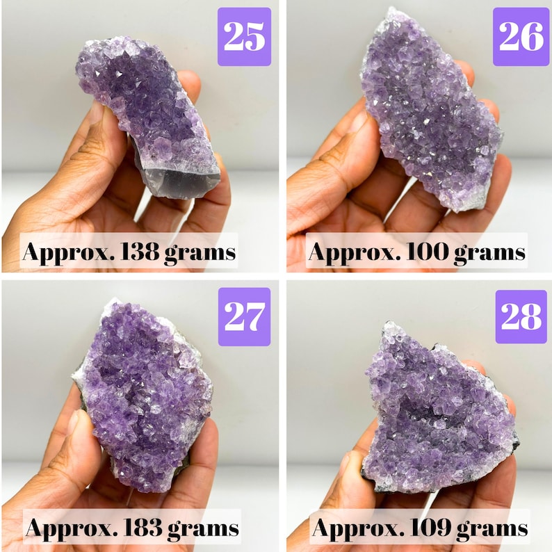 May include: Four amethyst crystal clusters labeled 25, 26, 27, and 28. The purple mineral specimens have jagged, crystalline surfaces. The weights are listed as approximately 138 grams, 100 grams, 183 grams, and 109 grams respectively.