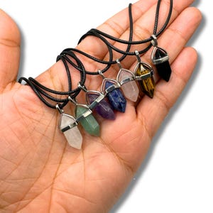 Puede incluir: Siete collares de punta de cristal con cordones negros. Los cristales son cuarzo transparente, aventurina verde, amatista, sodalita azul, cuarzo rosa, ojo de tigre y obsidiana negra.