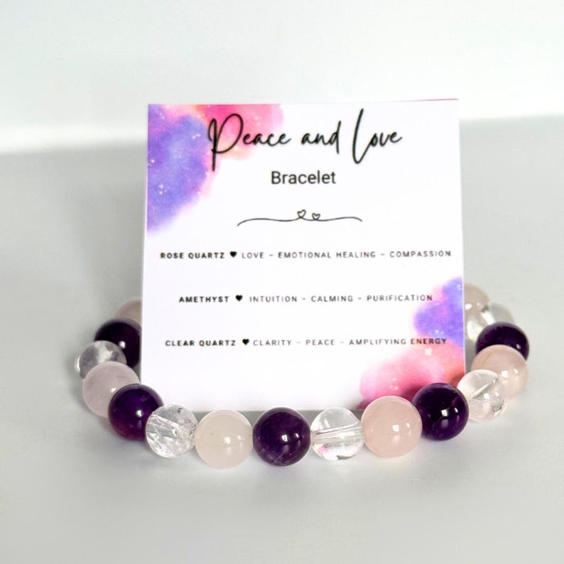 May include: A bracelet made with rose quartz, amethyst, and clear quartz beads. The bracelet is on a white background with a card that reads "Peace and Love Bracelet" and lists the properties of each stone.