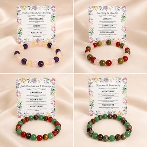 K&ouml;nnte beinhalten: Vier Edelsteinarmb&auml;nder mit Informationskarten. Die Armb&auml;nder haben Perlen in verschiedenen Farben, darunter Rosa, Gelb, Lila, Gr&uuml;n und Braun. Die Karten zeigen Text &uuml;ber die Eigenschaften der Steine, wie Rosenquarz, Citrin und Amethyst.