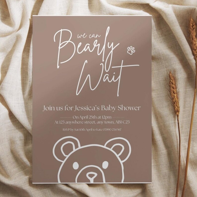 Puede incluir: Invitaci&oacute;n a un baby shower con fondo marr&oacute;n y texto blanco. El texto dice "Bearly Wait" e incluye detalles para el baby shower de Jessica el 25 de abril. Una ilustraci&oacute;n de oso de peluche est&aacute; en la parte inferior.