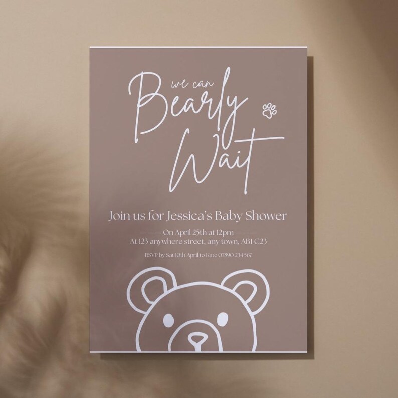 Puede incluir: Una invitaci&oacute;n de baby shower de color topo con texto blanco y una ilustraci&oacute;n de oso. La invitaci&oacute;n dice "Bearly Wait" e incluye detalles para el baby shower de Jessica, incluyendo la fecha, hora y lugar.