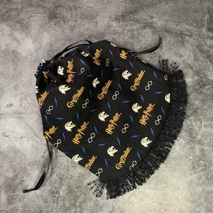 Peut inclure: Sac à cordon noir sur le thème d'Harry Potter et Gryffondor. Le sac est orné d'une frange noire et présente un motif répété du logo d'Harry Potter, d'éclairs et de l'emblème de Gryffondor.
