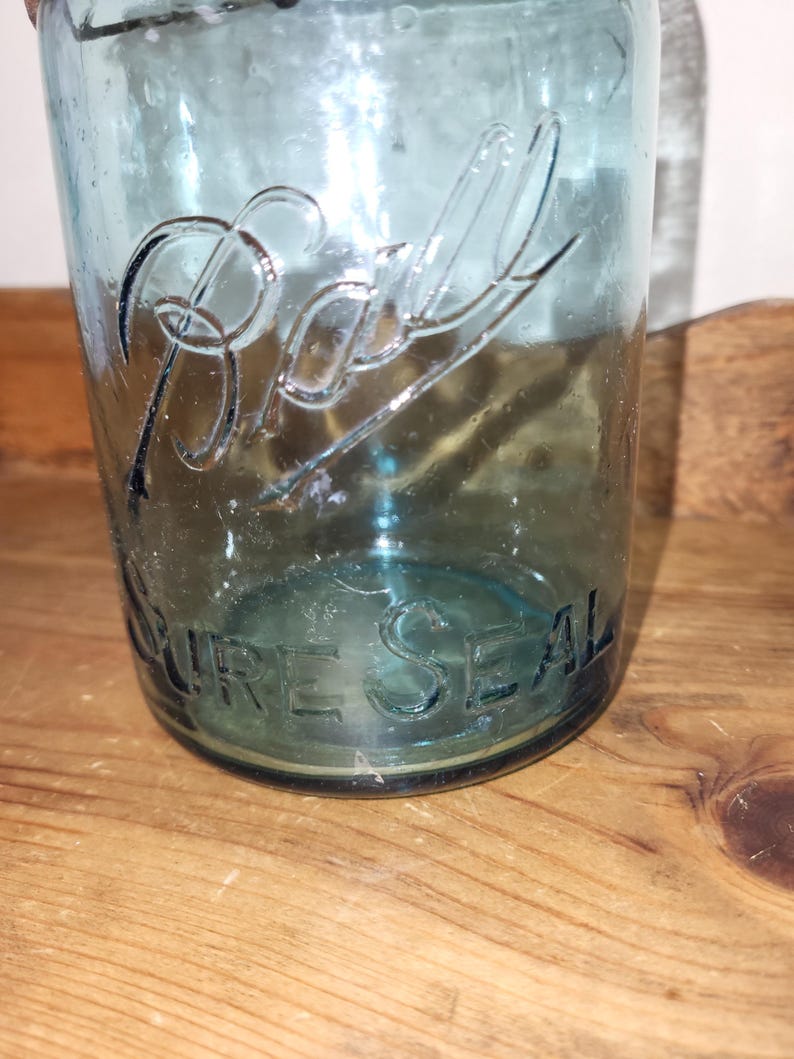May include: A vintage blue glass Ball jar with the text "PURE SEAL" embossed on the bottom.