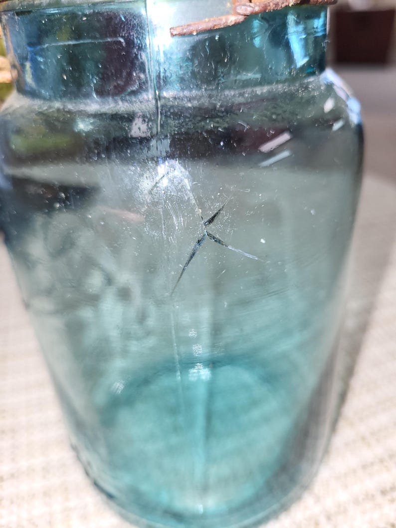May include: A vintage blue glass jar with a metal lid and a crack in the glass.