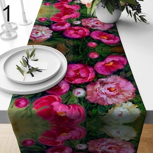 Puede incluir: Un camino de mesa floral con un vibrante estampado de peonías rosas sobre un fondo verde. El camino de mesa está decorado con una variedad de tamaños y tonos de peonías, creando un diseño exuberante y artístico. El camino de mesa está colocado sobre una mesa blanca.