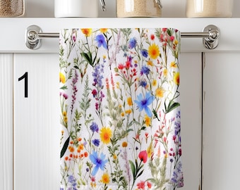 May include: A white rectangular kitchen towel featuring a colourful botanical print of various wildflowers including yellow, blue, pink, and purple blossoms with green stems and leaves. The number 1 is printed in black on the left side of the towel.