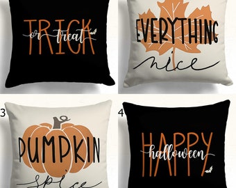 May include: Four square decorative throw pillows with Halloween-themed designs. The pillows feature phrases like "Trick or Treat," "Everything Nice," "Pumpkin Spice," and "Happy Halloween" in orange and white lettering on black and cream backgrounds.