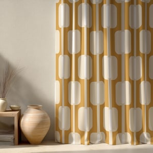 Può includere: Tenda color giallo senape e crema con un motivo geometrico ripetuto di rettangoli arrotondati e linee verticali. La tenda è appesa davanti a un muro beige. A sinistra c'è un tavolino di legno con un vaso e oggetti decorativi.