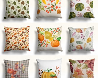 May include: Nine square throw pillows with autumn-themed designs. The pillows feature various patterns, including pumpkins, leaves, and floral arrangements in shades of orange, green, brown, and yellow. The pillows are square and appear to be made of a soft fabric.