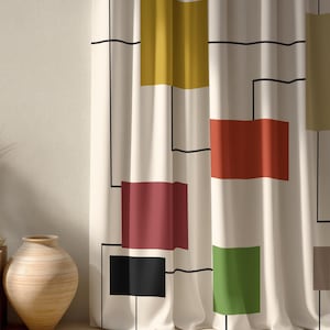 May include: Cream-colored curtain panel with a geometric design. The design features colorful rectangular blocks in shades of yellow, red, green, and black, outlined with black lines. The curtain is hanging in front of a neutral-colored wall.