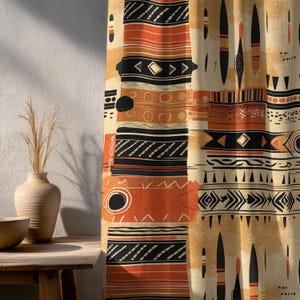 Könnte beinhalten: Beigefarbener Vorhang mit einem sich wiederholenden Muster aus schwarzen, orangefarbenen und cremefarbenen geometrischen Formen. Das Design umfasst Pfeile, Kreise und Linien und erzeugt eine Stammes- oder abstrakte Ästhetik. Der Vorhang wird teilweise von Sonnenlicht beleuchtet.