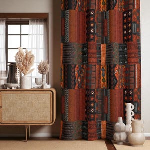 Könnte beinhalten: Ein bodenlanger Vorhang mit einem vertikalen Patchwork-Design und sich wiederholenden geometrischen Mustern in den Farben gebranntes Orange, Schwarz und Dunkelbraun. Der Stoff zeigt verschiedene, von Stämmen inspirierte Motive wie Kreise und Linien.