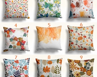 Puede incluir: Nueve diseños de almohadas diferentes con hojas de otoño en varios colores y patrones. Las almohadas son todas cuadradas y tienen un fondo blanco.