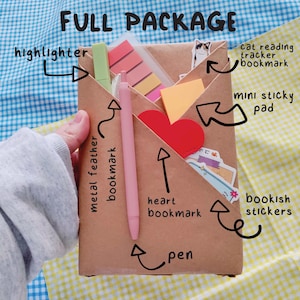 May include: A brown paper package labeled "FULL PACKAGE" contains a green highlighter, pink pen, sticky notes, heart bookmark, cat reading tracker bookmark, metal feather bookmark, and bookish stickers. The package is designed for book lovers.