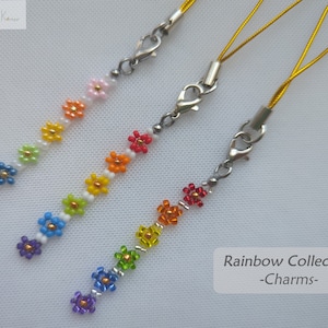 May include: Three rainbow charm keychains with silver clasps and gold cords. Each keychain features a row of colorful beaded flowers in a rainbow pattern.