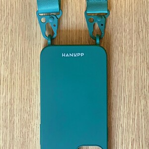 May include: Teal phone case with a matching teal strap. The phone case has the brand name "HANYPP" printed on it. The strap has the brand name "HANYPP" printed on the strap. The strap is attached to the phone case with teal metal clasps.